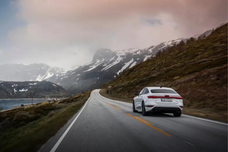 Audi A6 e-tron blanco en conducción por una carretera de montaña