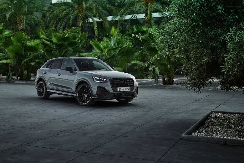 Audi Q2 gris visto de frente y lateral en un entorno exterior