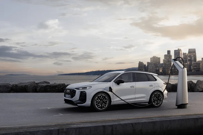 Audi Q3 e-hybrid blanco cargándose con una ciudad al fondo