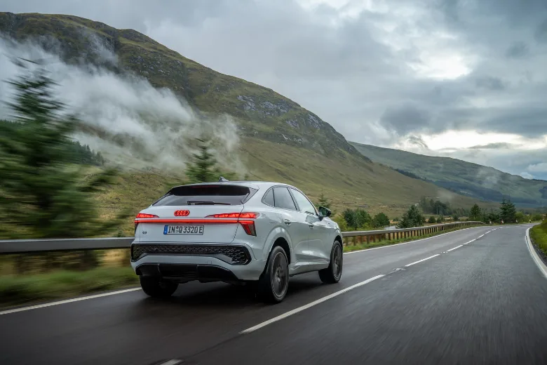 Audi Q3 gris visto desde la parte trasera en carretera de montaña
