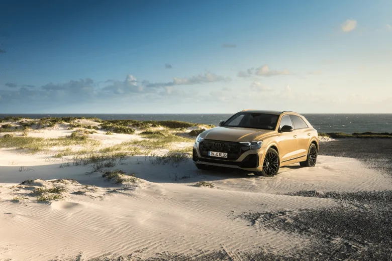 Audi Q8 color crema visto de frente en una playa